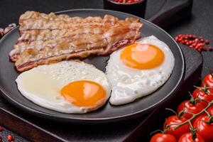 English breakfast with fried eggs, bacon, beans, tomatoes, spices and herbs photo