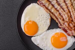 English breakfast with fried eggs, bacon, beans, tomatoes, spices and herbs photo