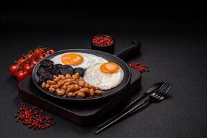 English breakfast with fried eggs, bacon, beans, tomatoes, spices and herbs photo