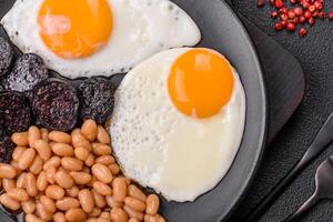English breakfast with fried eggs, bacon, beans, tomatoes, spices and herbs photo