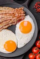 English breakfast with fried eggs, bacon, beans, tomatoes, spices and herbs photo