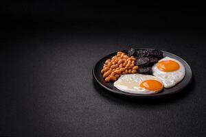 English breakfast with fried eggs, bacon, beans, tomatoes, spices and herbs photo