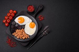 English breakfast with fried eggs, bacon, beans, tomatoes, spices and herbs photo