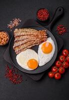English breakfast with fried eggs, bacon, beans, tomatoes, spices and herbs photo
