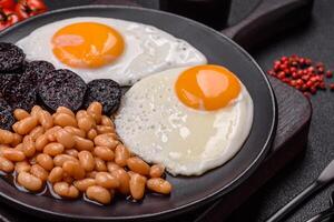 English breakfast with fried eggs, bacon, beans, tomatoes, spices and herbs photo