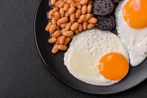 English breakfast with fried eggs, bacon, beans, tomatoes, spices and herbs photo