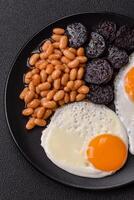 English breakfast with fried eggs, bacon, beans, tomatoes, spices and herbs photo