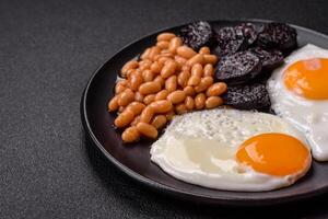 English breakfast with fried eggs, bacon, beans, tomatoes, spices and herbs photo
