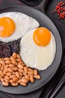 English breakfast with fried eggs, bacon, beans, tomatoes, spices and herbs photo