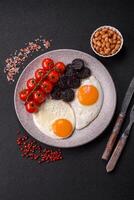 English breakfast with fried eggs, bacon, beans, tomatoes, spices and herbs photo