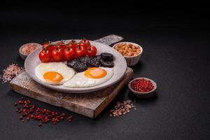 English breakfast with fried eggs, bacon, beans, tomatoes, spices and herbs photo