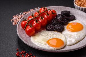 English breakfast with fried eggs, bacon, beans, tomatoes, spices and herbs photo