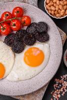 English breakfast with fried eggs, bacon, beans, tomatoes, spices and herbs photo