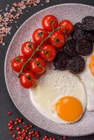 English breakfast with fried eggs, bacon, beans, tomatoes, spices and herbs photo