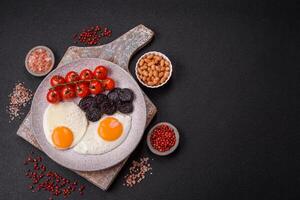 English breakfast with fried eggs, bacon, beans, tomatoes, spices and herbs photo