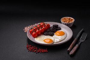 English breakfast with fried eggs, bacon, beans, tomatoes, spices and herbs photo