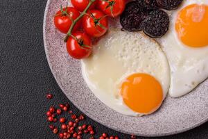 English breakfast with fried eggs, bacon, beans, tomatoes, spices and herbs photo