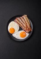 English breakfast with fried eggs, bacon, beans, tomatoes, spices and herbs photo