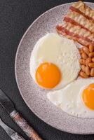 English breakfast with fried eggs, bacon, beans, tomatoes, spices and herbs photo