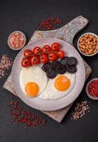 English breakfast with fried eggs, bacon, beans, tomatoes, spices and herbs photo
