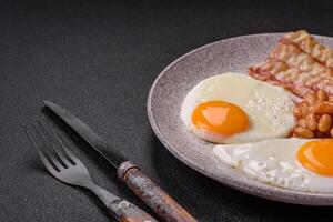 English breakfast with fried eggs, bacon, beans, tomatoes, spices and herbs photo