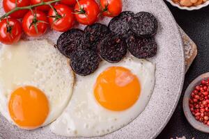 English breakfast with fried eggs, bacon, beans, tomatoes, spices and herbs photo
