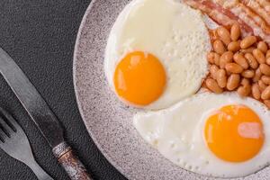 English breakfast with fried eggs, bacon, beans, tomatoes, spices and herbs photo