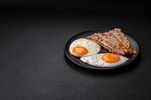 English breakfast with fried eggs, bacon, beans, tomatoes, spices and herbs photo