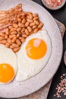 English breakfast with fried eggs, bacon, beans, tomatoes, spices and herbs photo