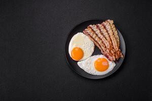 English breakfast with fried eggs, bacon, beans, tomatoes, spices and herbs photo
