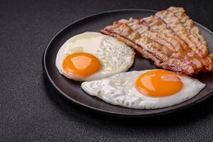 English breakfast with fried eggs, bacon, beans, tomatoes, spices and herbs photo