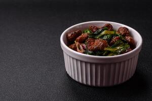Delicious warm salad with pieces of meat, spinach, tomatoes, salt, spices and herbs photo