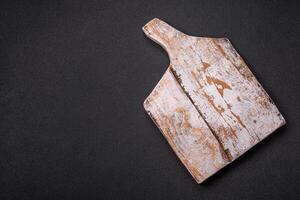 Empty wooden cutting board on dark textured concrete background photo