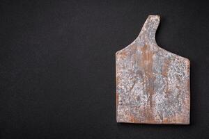 Empty wooden cutting board on dark textured concrete background photo