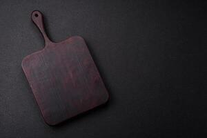 Empty wooden cutting board on dark textured concrete background photo