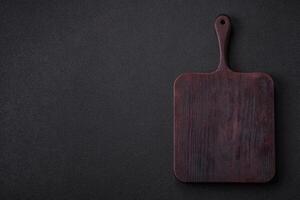 Empty wooden cutting board on dark textured concrete background photo