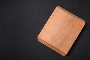 Empty wooden cutting board on dark textured concrete background photo