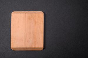 Empty wooden cutting board on dark textured concrete background photo
