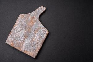 Empty wooden cutting board on dark textured concrete background photo