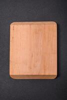 Empty wooden cutting board on dark textured concrete background photo