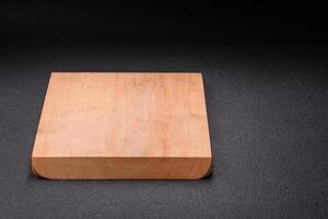 Empty wooden cutting board on dark textured concrete background photo