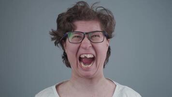 Woman without front tooth smiling stupidly looking at camera in the studio against a gray background. Toothless female makes funny face for the camera. Broken half of a front tooth in an adult woman. video