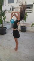 A girl is playing with a ball in the yard, under sunlight, surrounded by greenery video