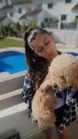 A woman is with a poodle dog by a pool on a sunny day, having a moment of affection and relaxation video