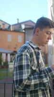A young man is using a phone outdoors in an urban area, checking messages and browsing the internet video