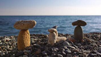 Balanced pebbles pyramid on the beach on sunny day and clear sky at sunset. Golden sea bokeh on background. Selective focus, zen stones on sea beach, meditation, spa, harmony, calm, balance concept. video
