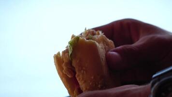 Silhouette of a man enjoying eating of a hamburger. Side view portrait of a person savoring a delicious, satisfying burger with great appetite. Fast food indulgence. video