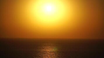 A red burning sunset over sea. Abstract nature summer ocean sea background. Small waves on golden warm water surface with bokeh lights from sun. Weather and climate change video