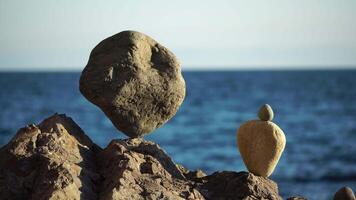 Balanced pebbles pyramid on the beach on sunny day and clear sky at sunset. Golden sea bokeh on background. Selective focus, zen stones on sea beach, meditation, spa, harmony, calm, balance concept. video