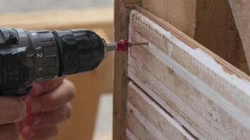 A man hands using a power tool fastens a board with a screw. Slow motion video